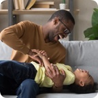 Daughter laughs as her father tickles her.